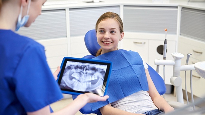Dentist reviewing young patient's digital dental x-rays