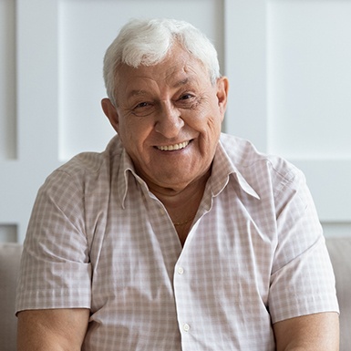 A person smiling on a couch after dental implant tooth replacement