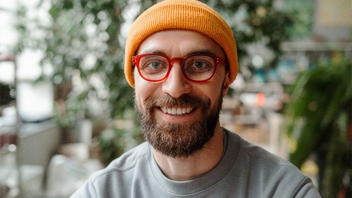 A smiling man with orange glasses