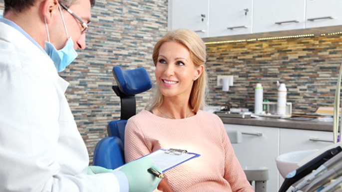 Smiling, female All-on-4 patient talking to implant dentist