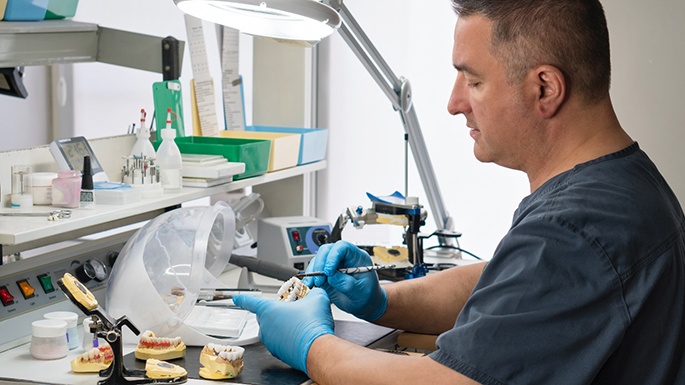 a dental lab technician crafting a dental bridge