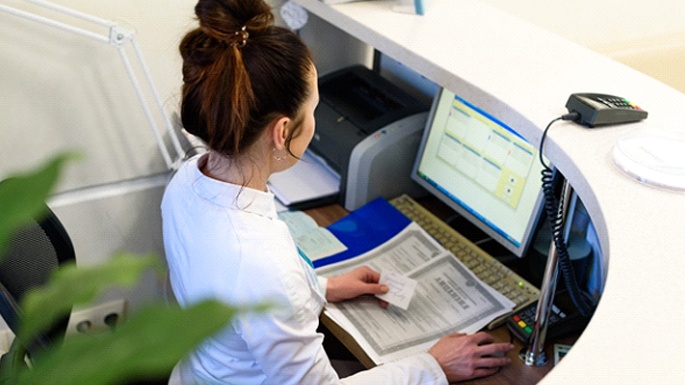 A female dental receptionist entering patient information into her computer