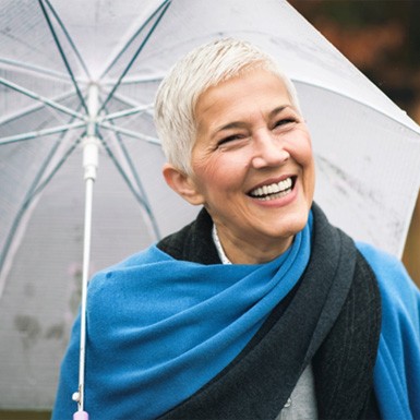 Senior woman with an umbrella outside smiling