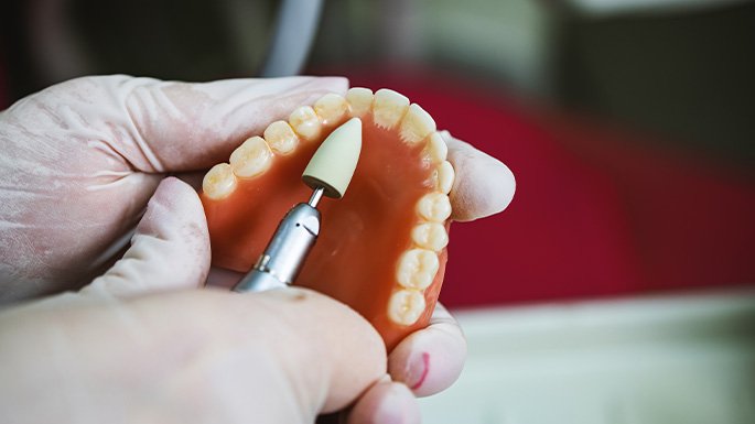 hands cleaning removeable dentures with a brush