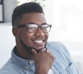 Man in denim shirt resting his chin in his hand