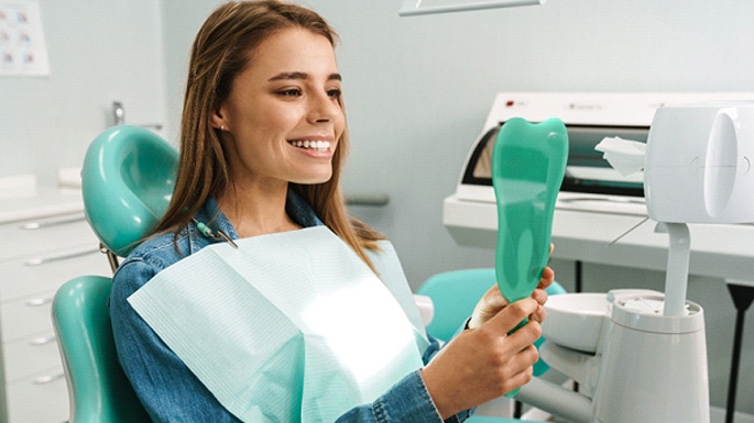 Patient holding mirror at appointment with Guardian dentist in Bustleton