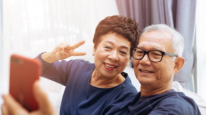 Older couple with dental implants in Philadelphia taking a selfie