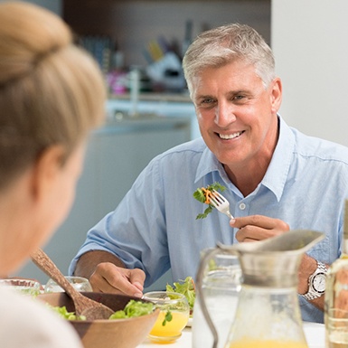 Older man with dental implants in Philadelphia enjoying healthy meal