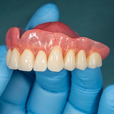 Implant dentist in Philadelphia holding a dental implant