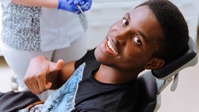 Man in dental chair giving a thumbs up