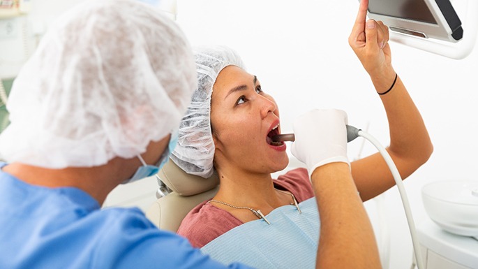 Dental patient pointing at monitor displaying images from intraoral camera