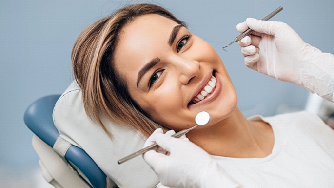 A young woman lying back in a dentist’s chair undergoing a regular dental checkup