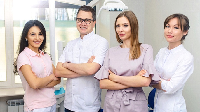 A team of dental professionals standing with their arms crossed and smiling