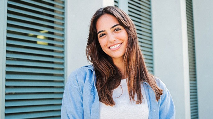 Woman with white teeth smiling while standing outside