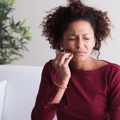 a woman touching her cheek due to gum discomfort