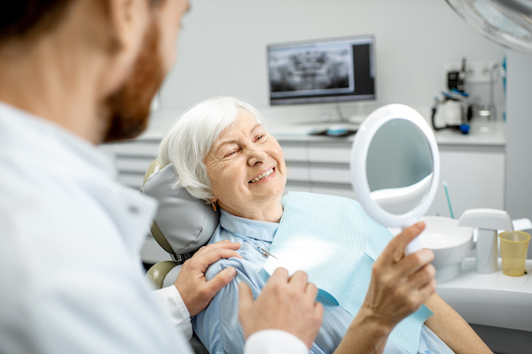 older woman smiling at reflection in dental office