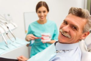 a dentist showing her patient how to care for his dentures