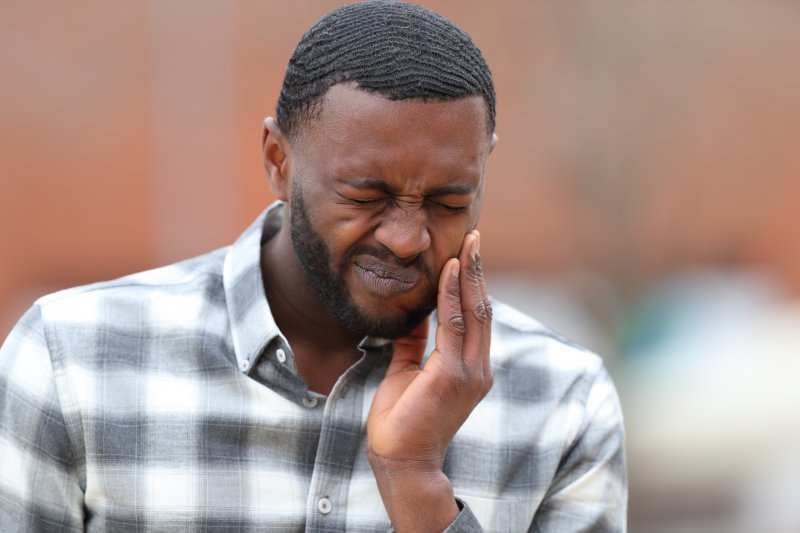 A man holding his jaw due to gum irritation