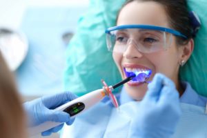 Woman having cosmetic dental bonding cured