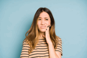 Woman rubbing her jaw because of wisdom tooth pain
