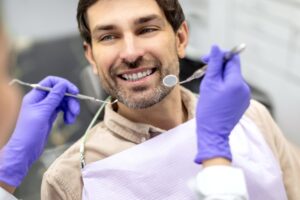 Man in dental chair smiling about to undergo exam